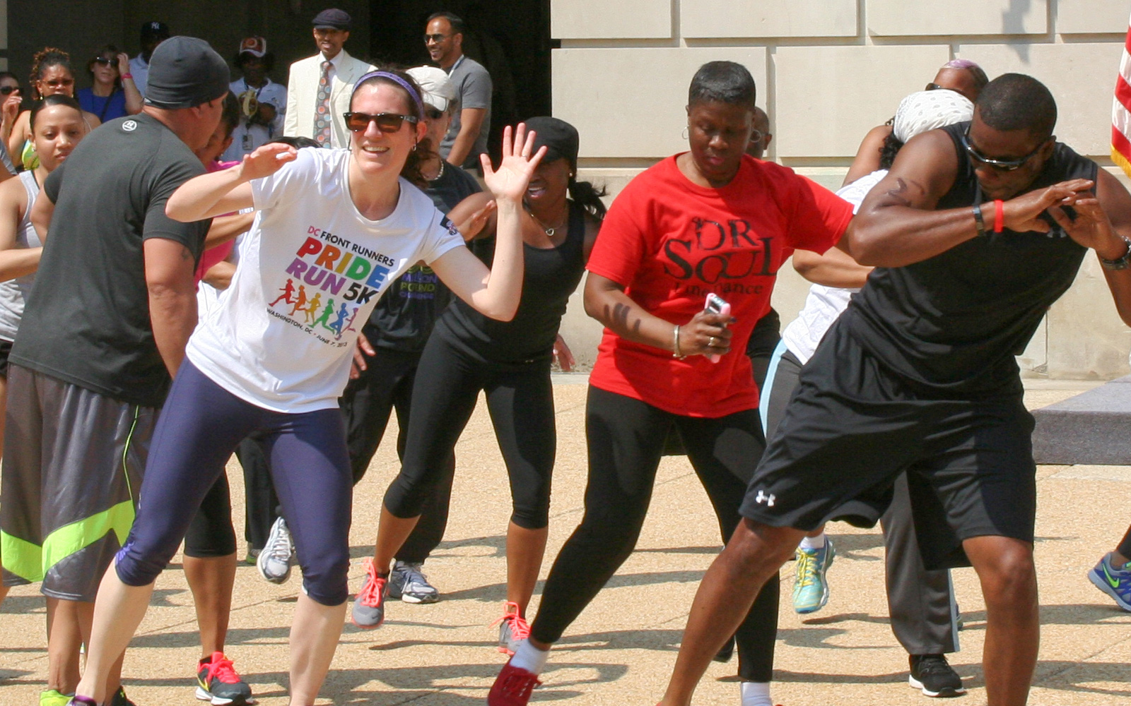 Group of EPA employees participating in outdoors synchonized aerobic dance exercises in an urban environment on a sunny day