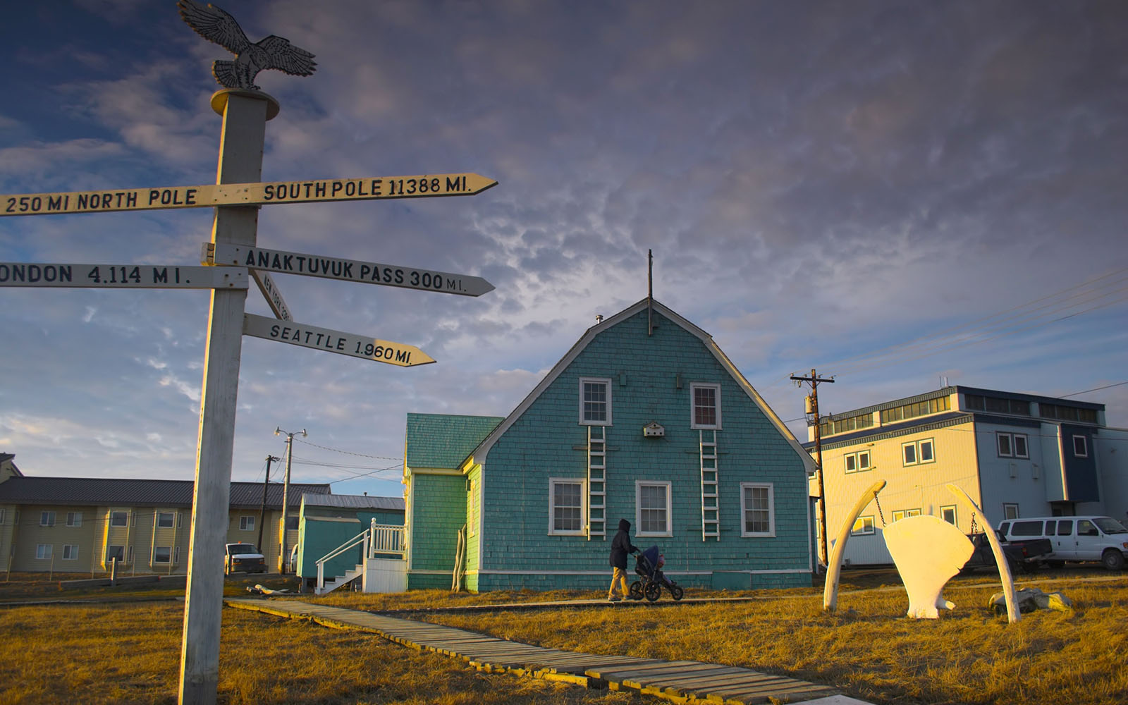 Photo of houses in Barrow, Alaska and a signpost pointing to far-away places