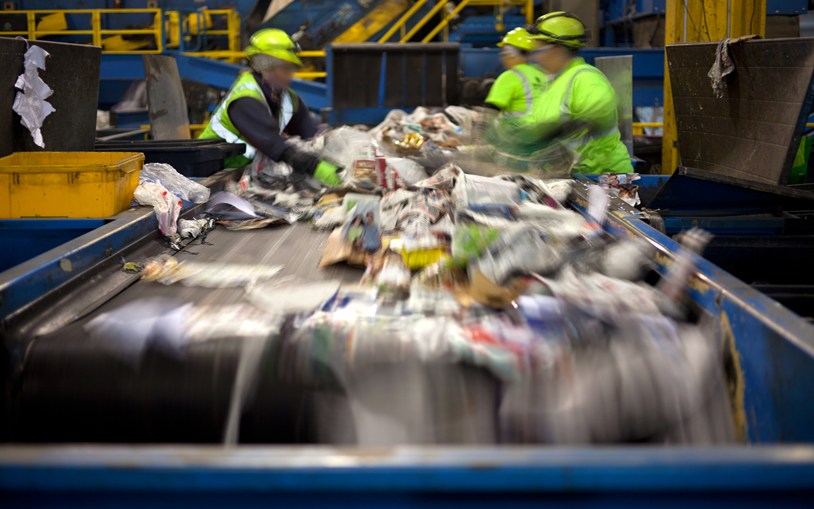 recycling workers sort materials on a conveyer belt.