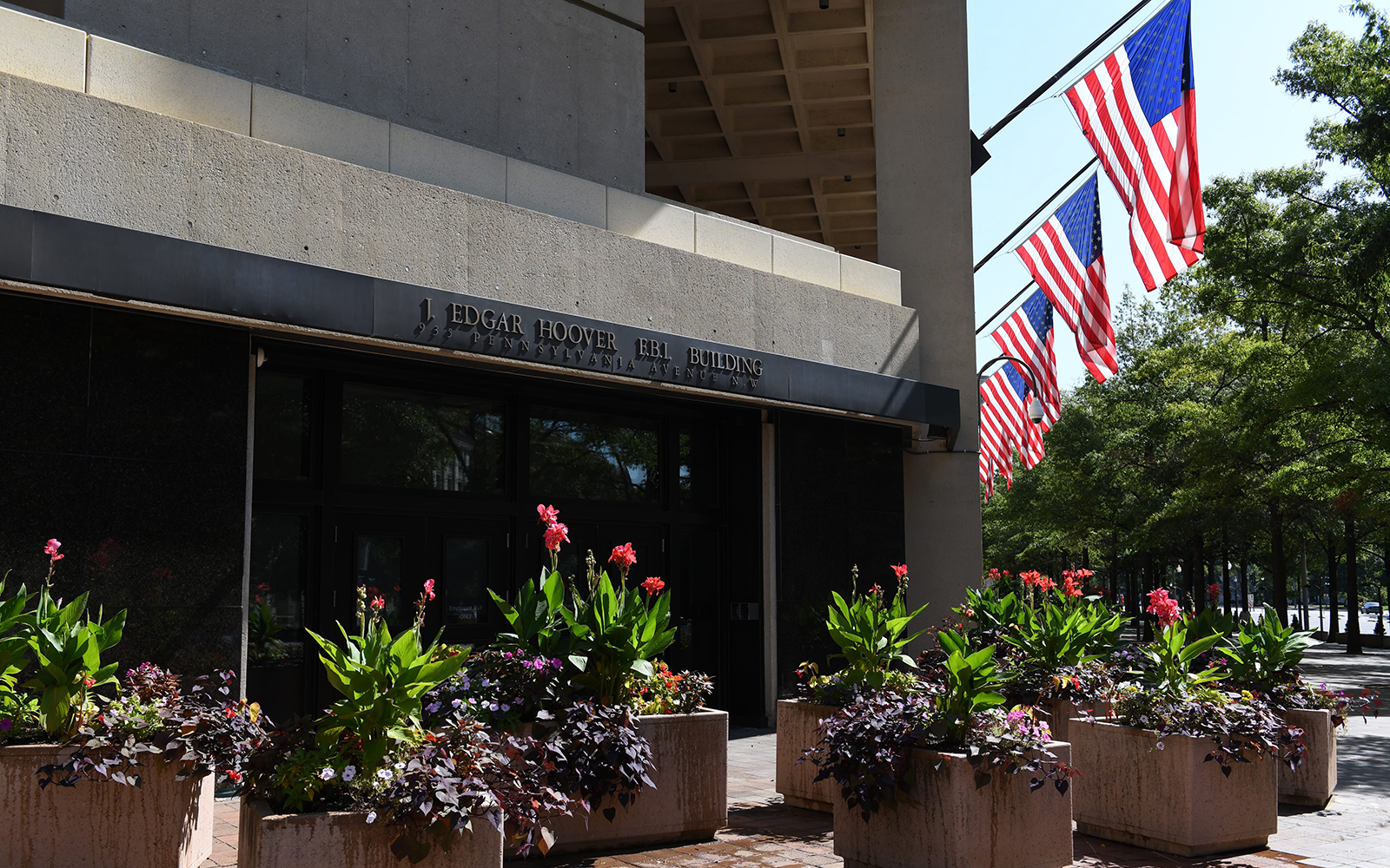 photo of FBI building front with several American flags and planters