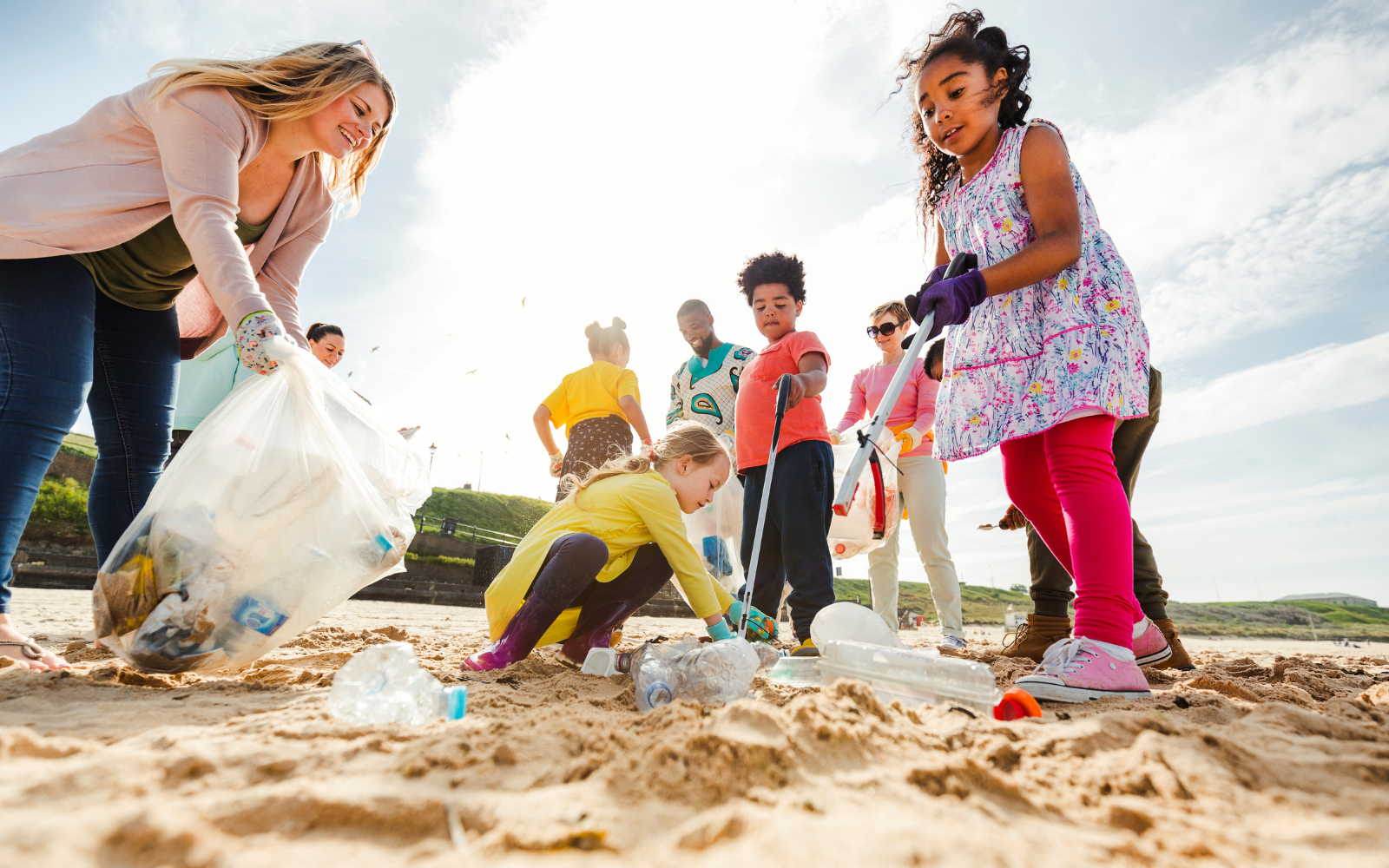 children and adult volunteers picking up trash at the beach