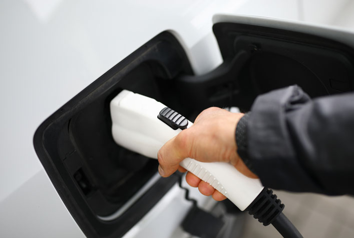 Photo of a persona plugging in their electric vehicle