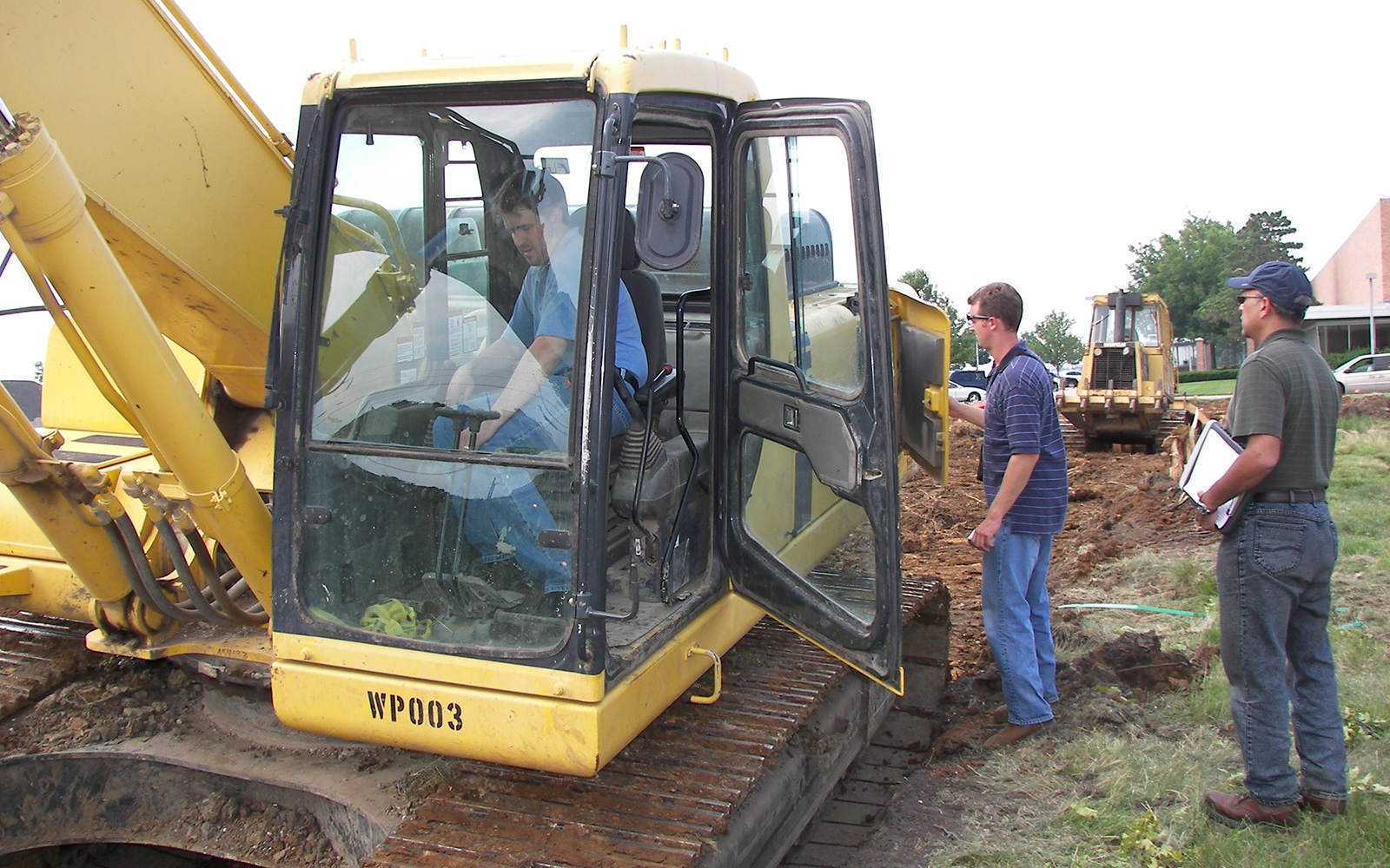 Crane operator cab, with one man inside and two others standing right outside, as part of an in-use emissions and activity measurement study