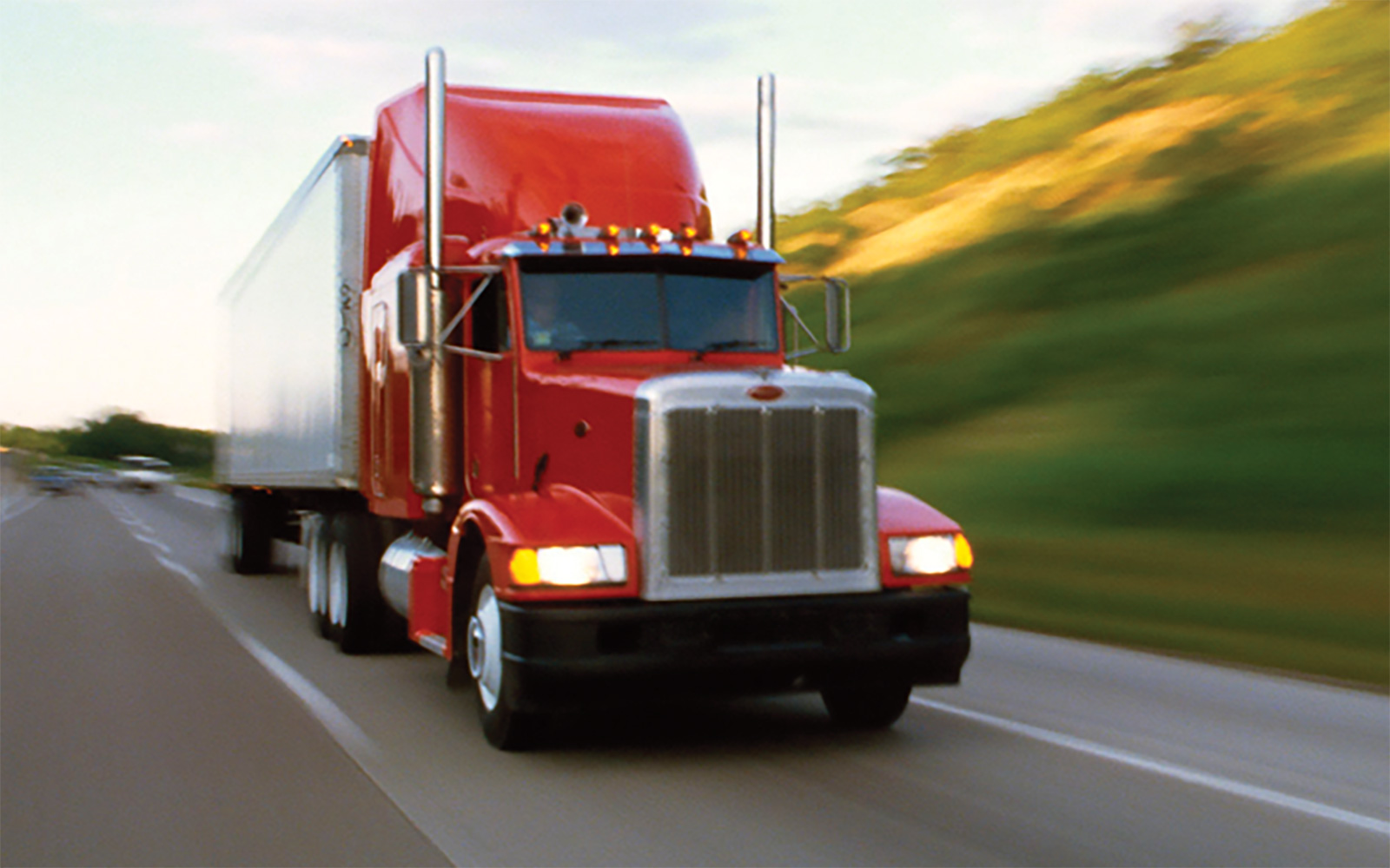 Large red freight truck driving down a highway