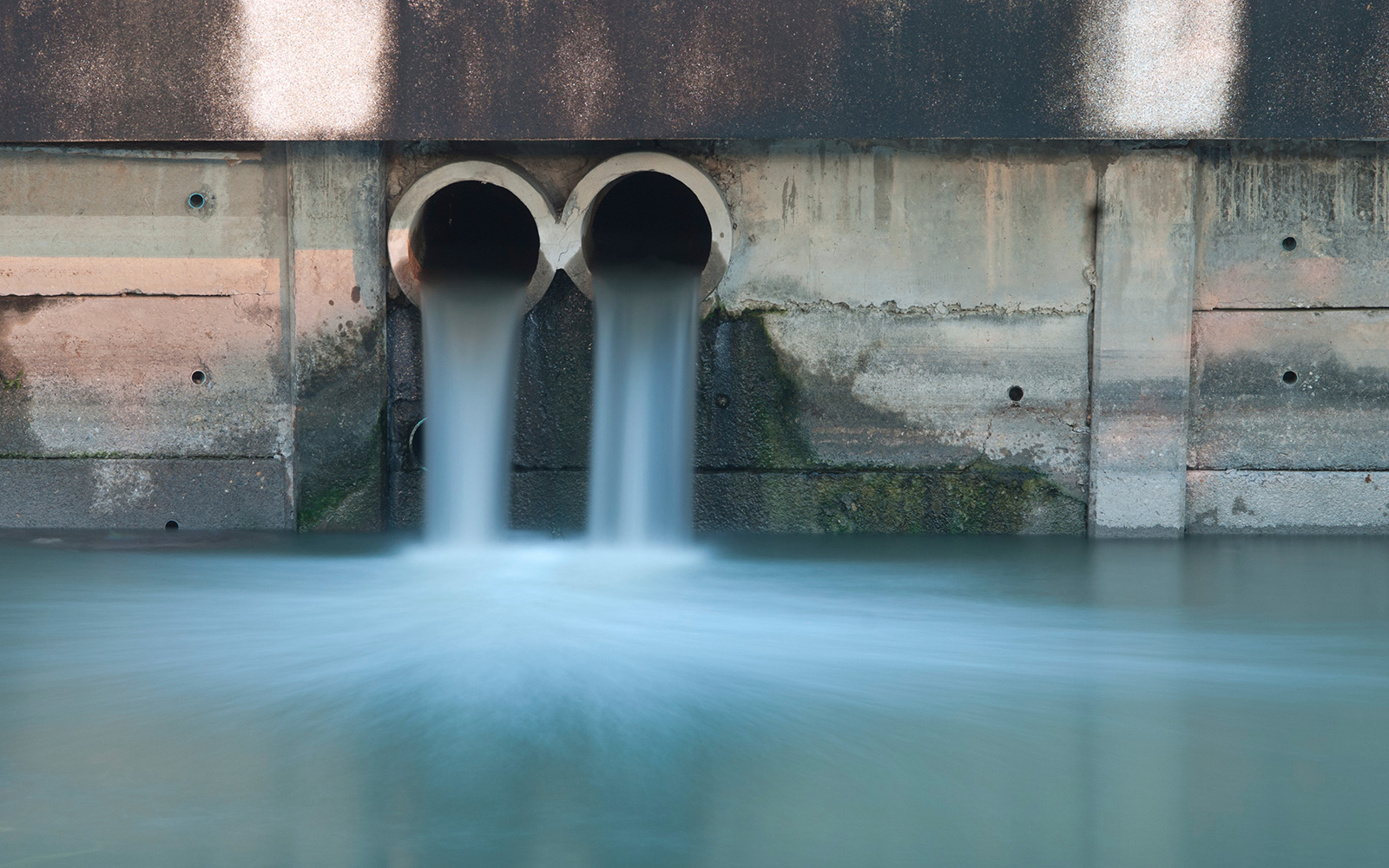 Effluent flowing from two discharge pipes into a water body