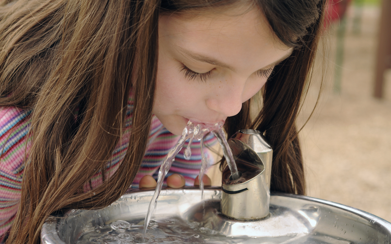 child drinking from water fountain