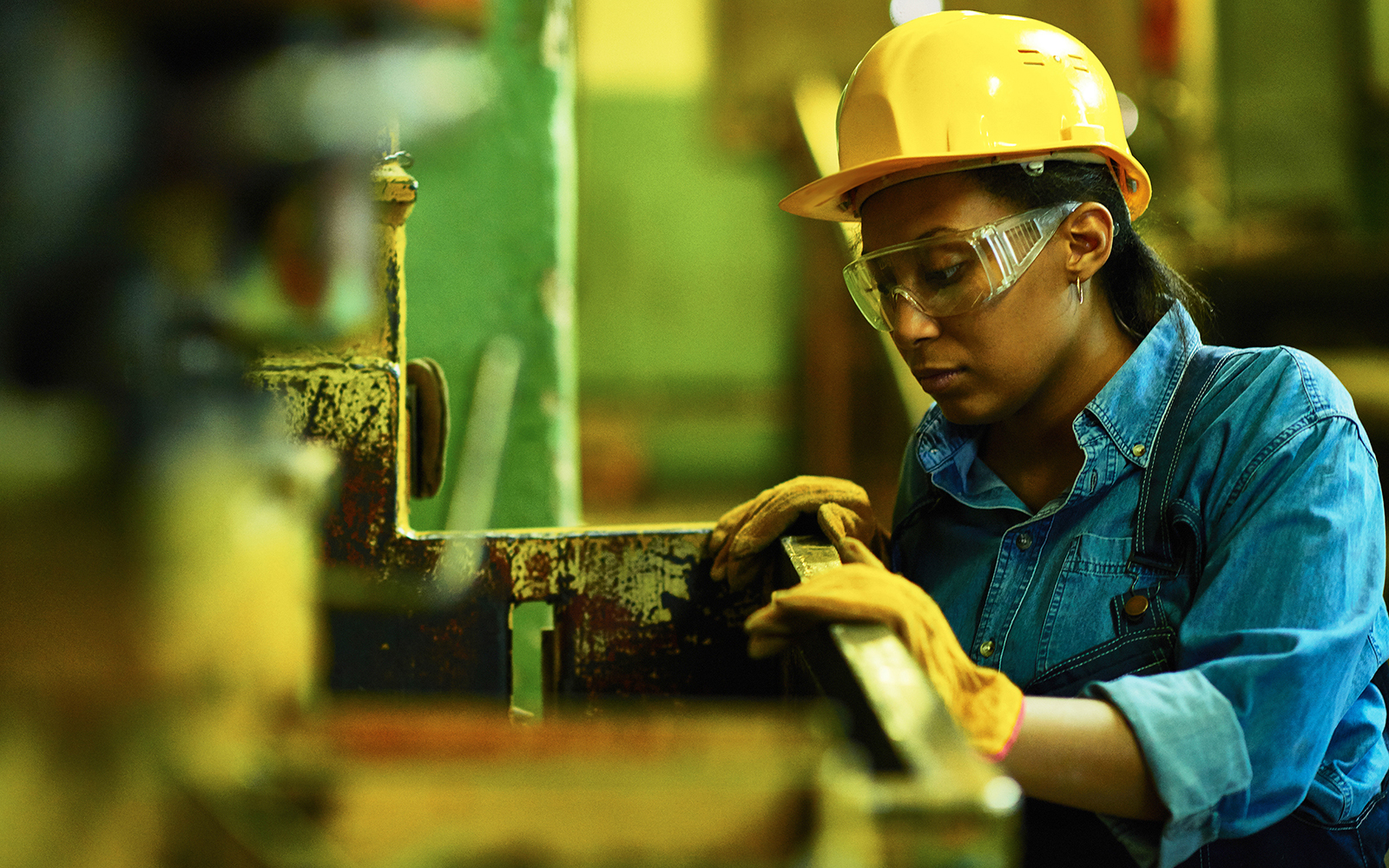 Industrial worker in protective hard hat, safety glasses, and gloves