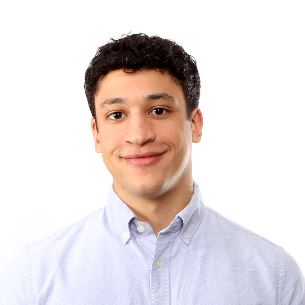 Man in a light blue shirt smiling with mouth closed