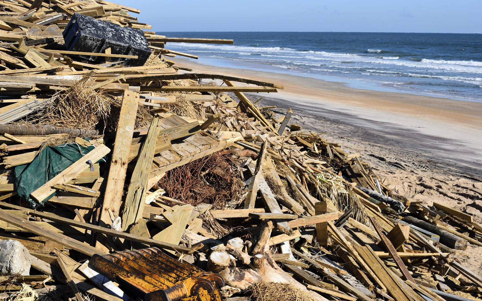A pile of debris, including wood and trash, on the beach.