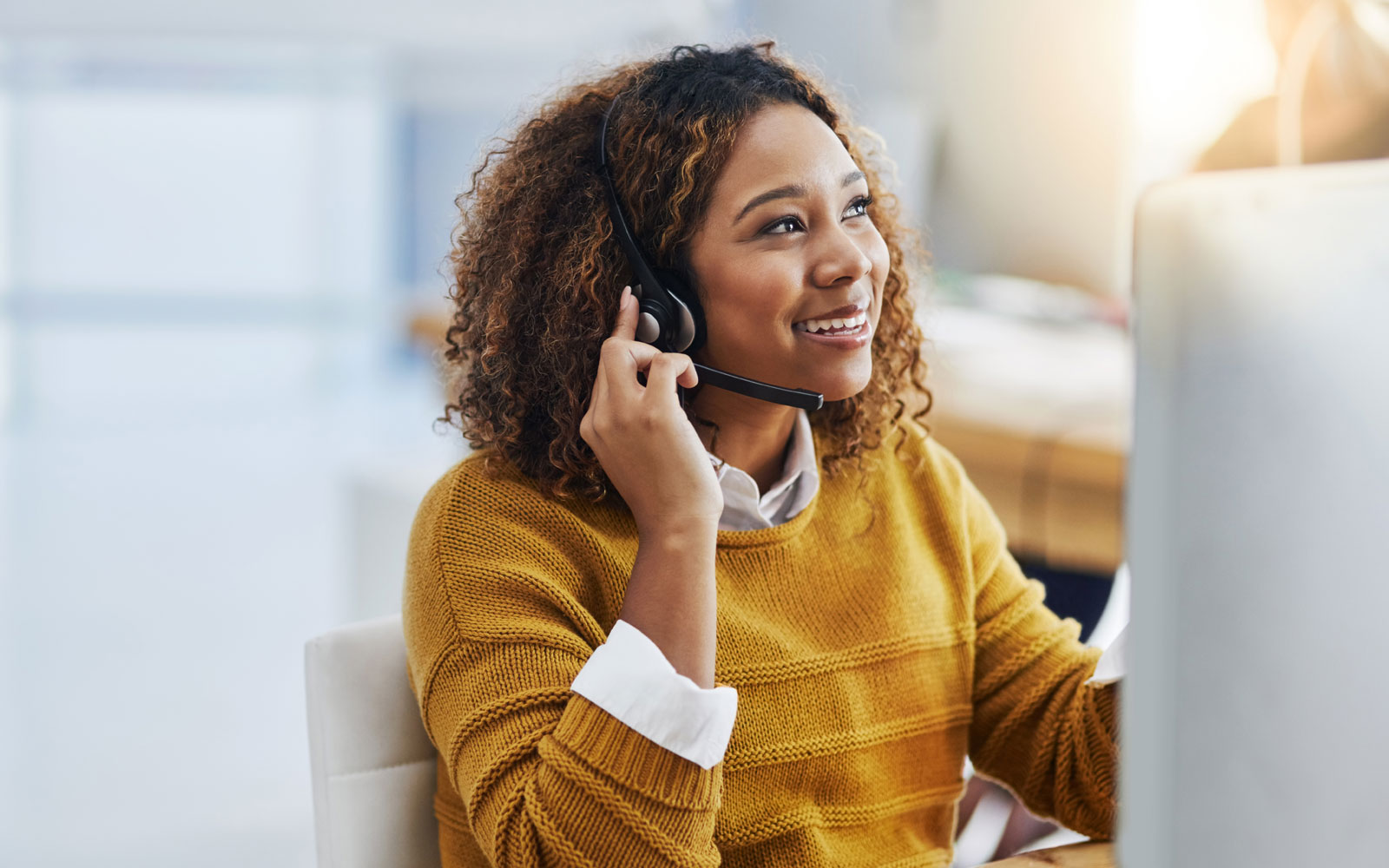 Photo of person sitting in front of a computer with a phone headset