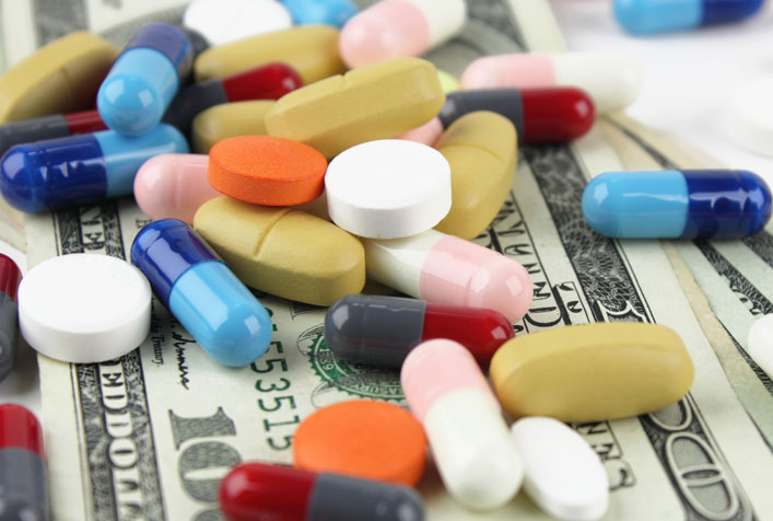 Photo of various pills loosely piled on top of a stack of cash