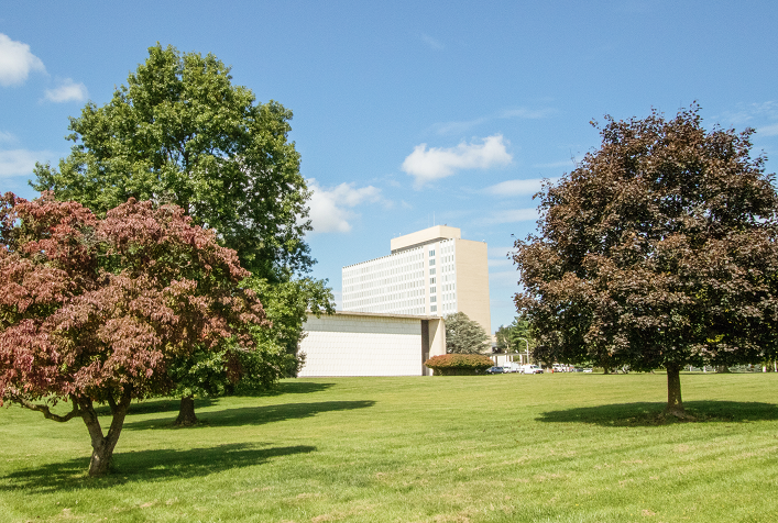 Photo of NIST Campus in distance looking past ornamental trees and green grass