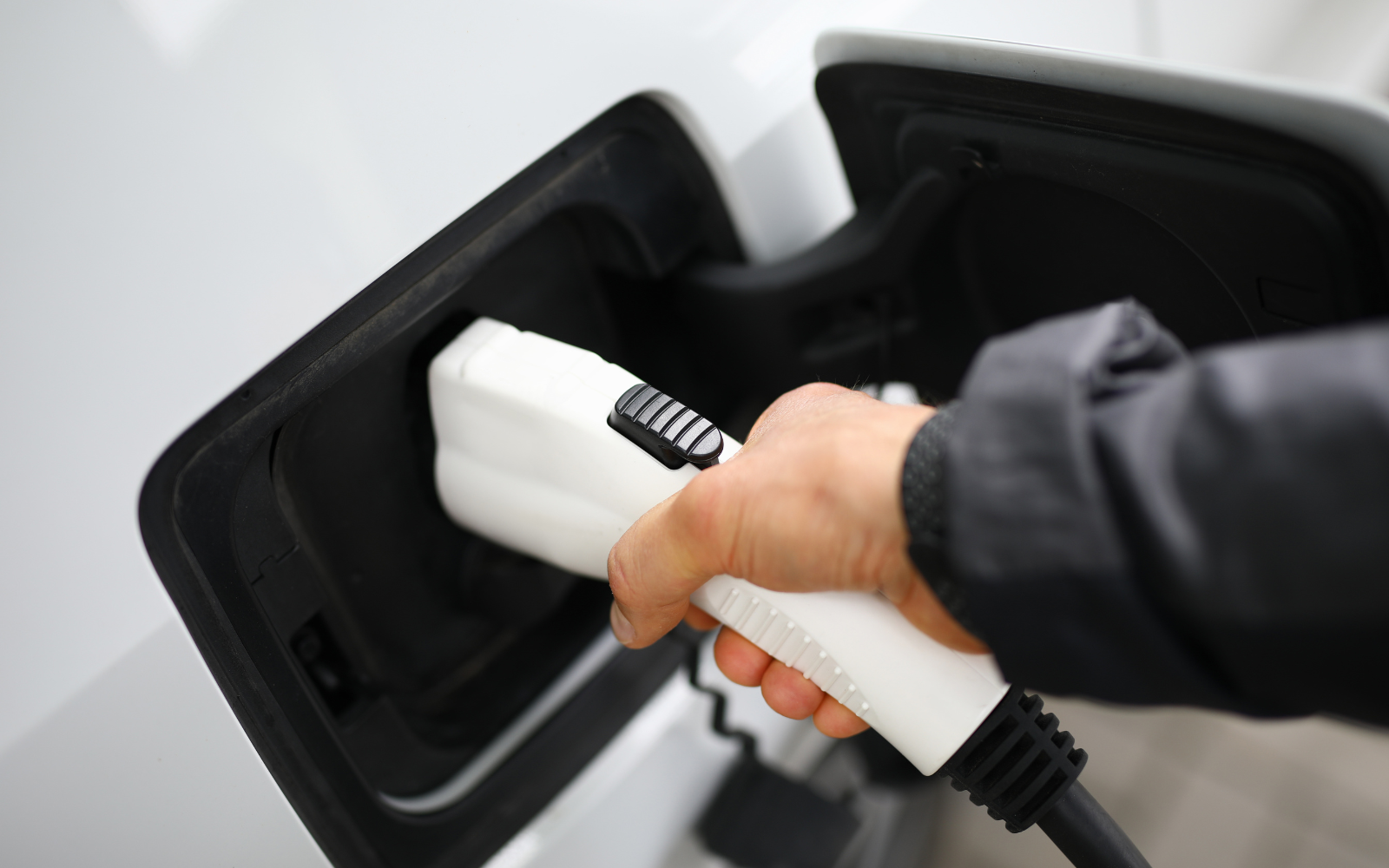 a person charges an electric car. close-up of charging port.