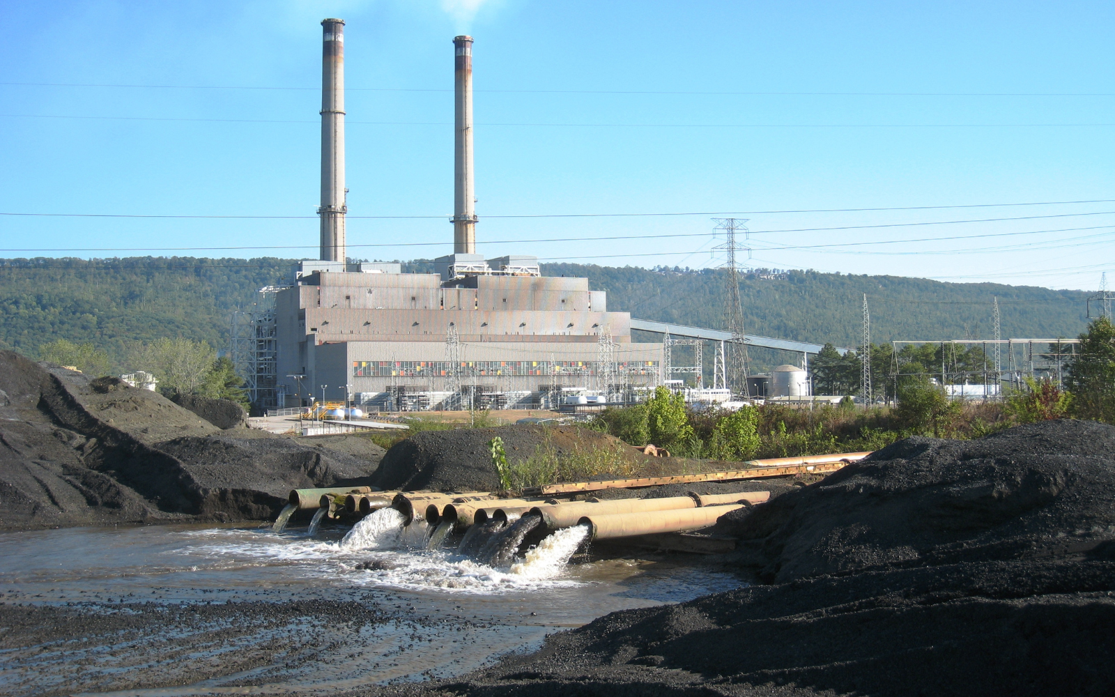 A power plant and pipes sending water into a nearby waterbody.