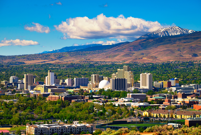 photo showing view of Nevada's city with mountains blue skies, and puffy clouds in the distance