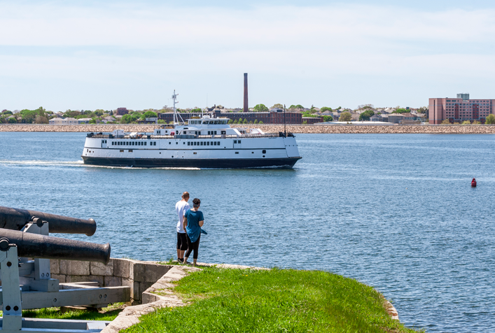 Massachusetts port with ship arriving. 2 people watching the approach