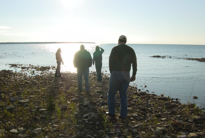photo of 4 people standing along a rocky shoreline