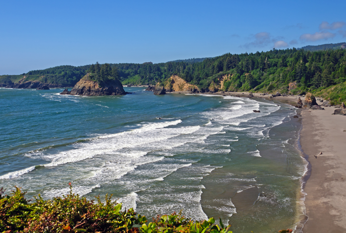 Photo of a california coastline with gentle waves hitting the beach. 