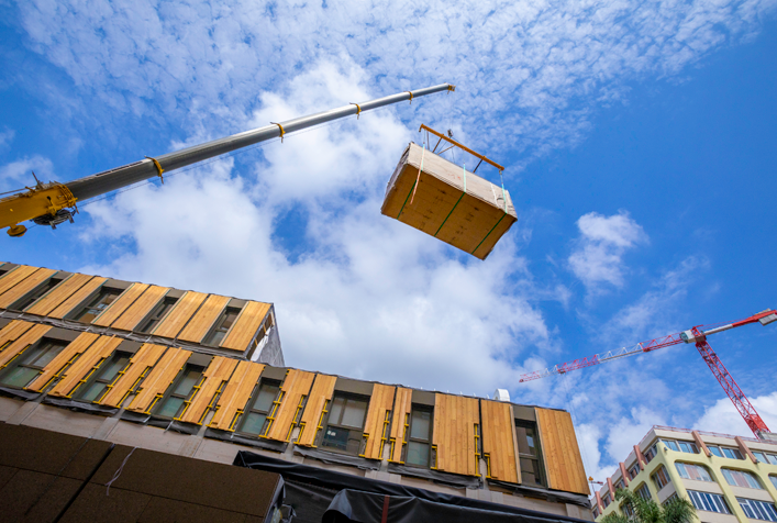 view looking upward at construction material being lifted by a crane