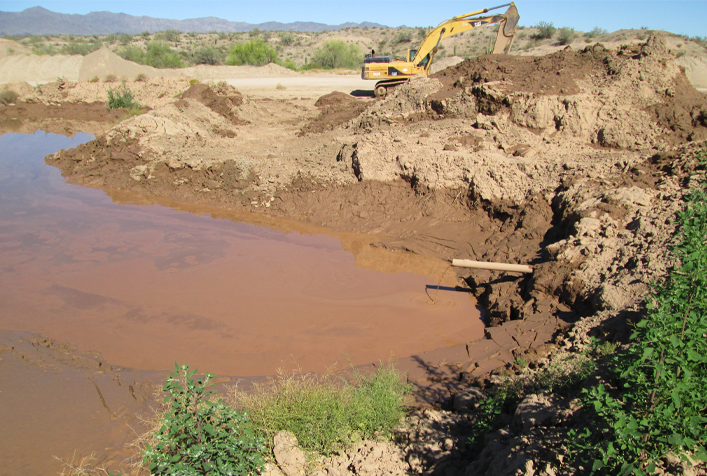 Image of an AZ landscape showing an excavator digging from groundwater and making piles of soil