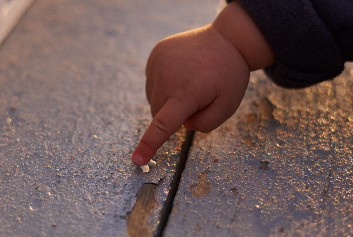 image of toddlers' hand touching chipping surface paint