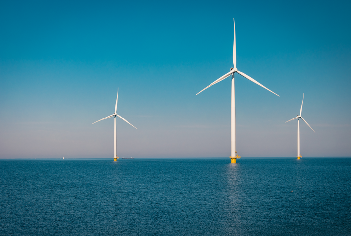 Aerial drone view of three wind turbines in the ocean