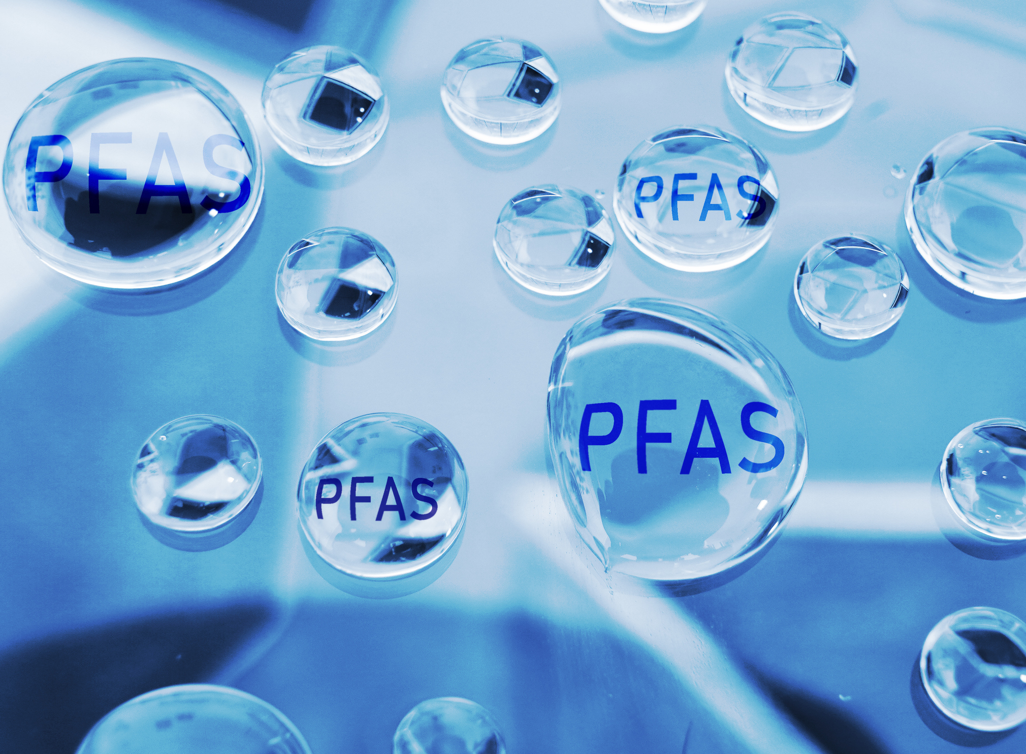 Illustration of water droplets with "PFAS" written inside them.